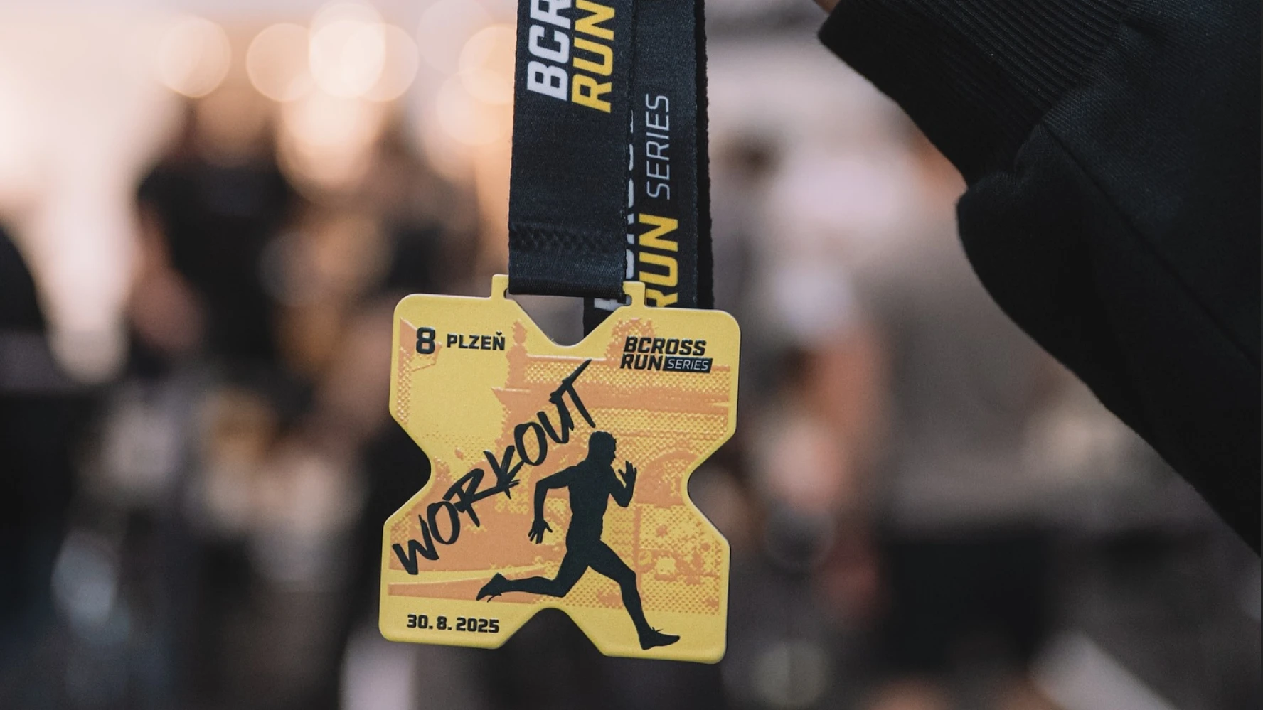 Bcross Run Plzeň workout finisher medal — gold X-shaped medal with runner silhouette on Bcross Run Series lanyard
