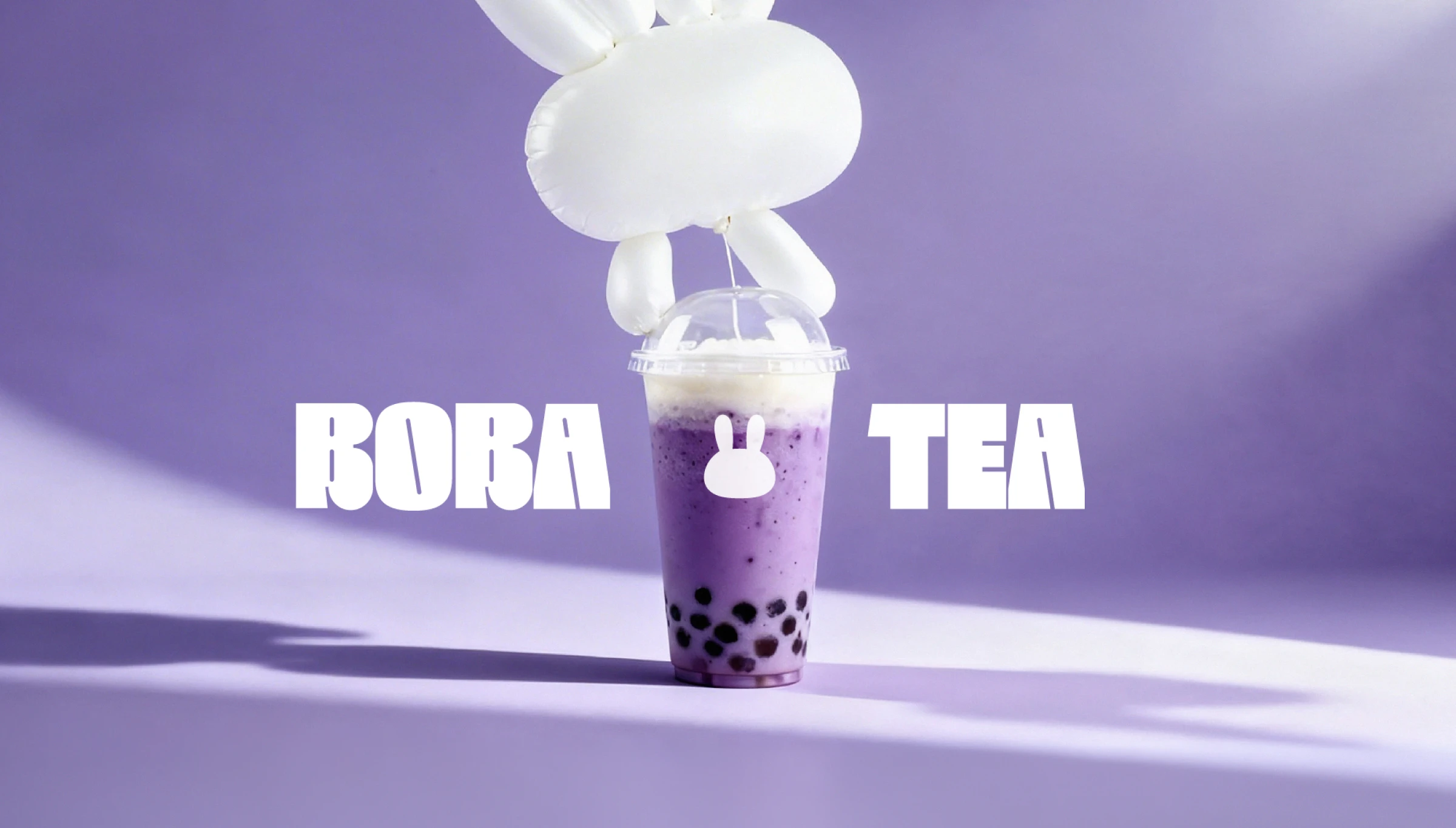 Boba tea brand photo — purple bubble tea cup with bunny silhouette logo and balloon rabbit on a lavender backdrop